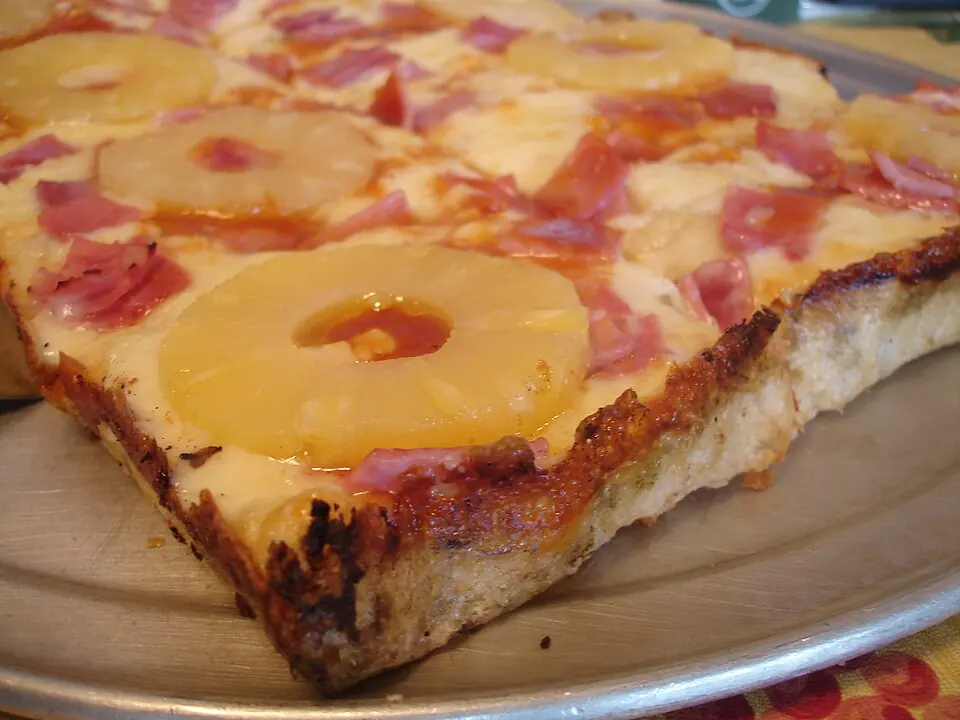 O felie de pizza cu șuncă și ananas